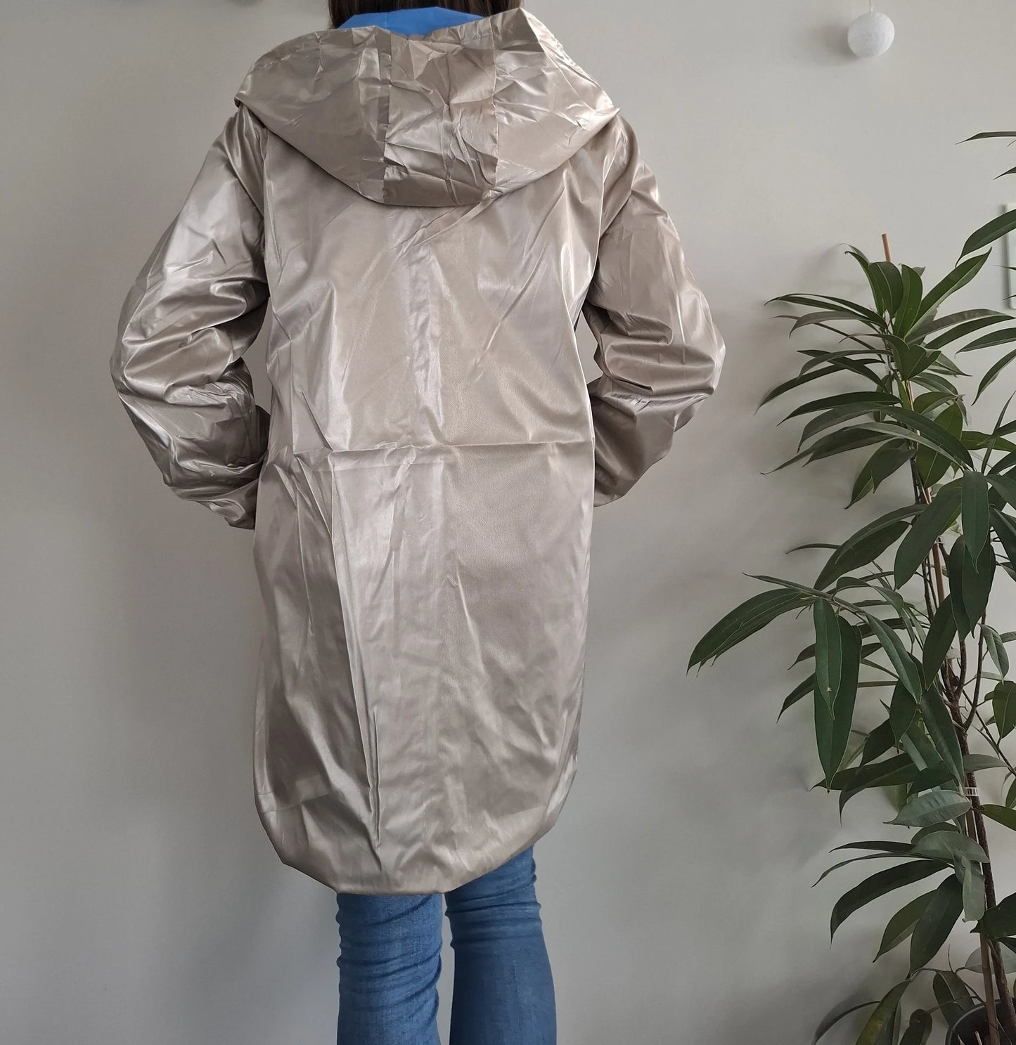 Vue de dos du manteau long réversible imperméable doré Melya Melody avec capuche, porté sur un jean bleu