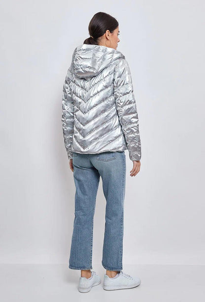 Woman wearing silver quilted short jacket with hood, jeans and sneakers, Le Petit Placard