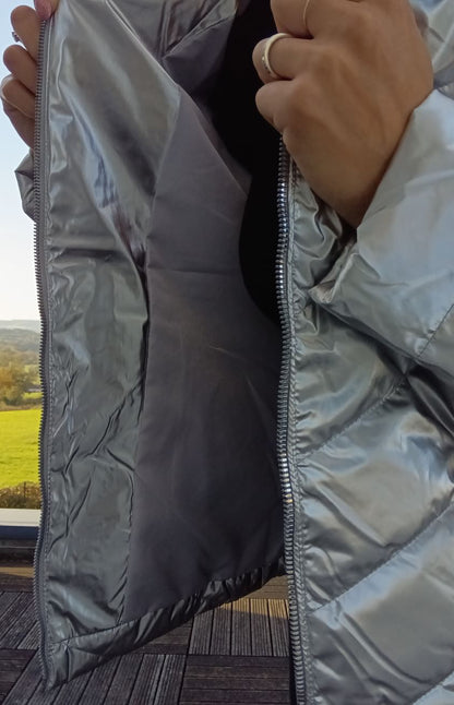 Close-up of a person opening a shiny silver Laura Jo raincoat outdoors, Le Petit Placard