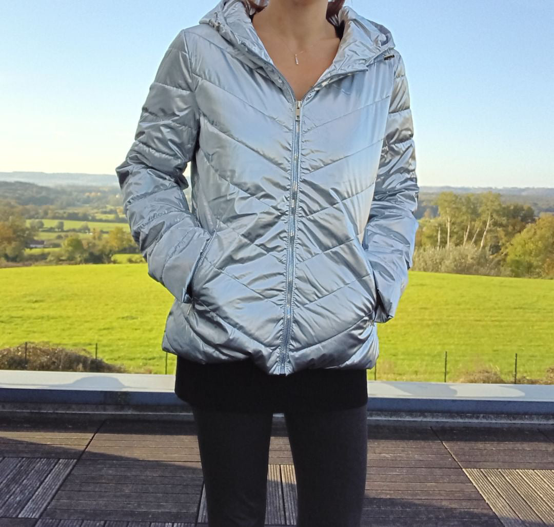 Woman wearing a silver Laura Jo hooded puffer jacket outdoors, trendy raincoat fashion