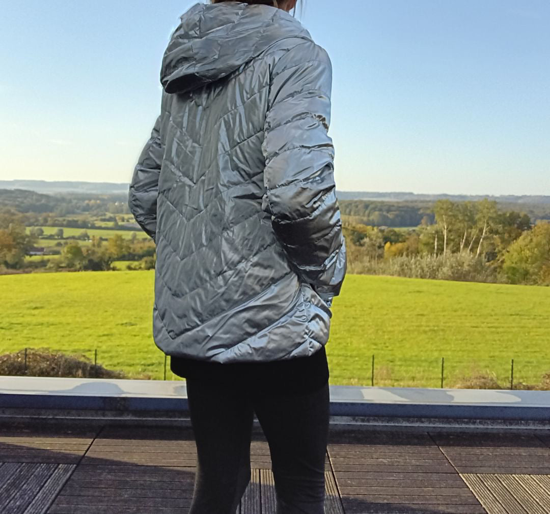Woman in silver Laura Jo raincoat from Le Petit Placard, standing outdoors on a terrace