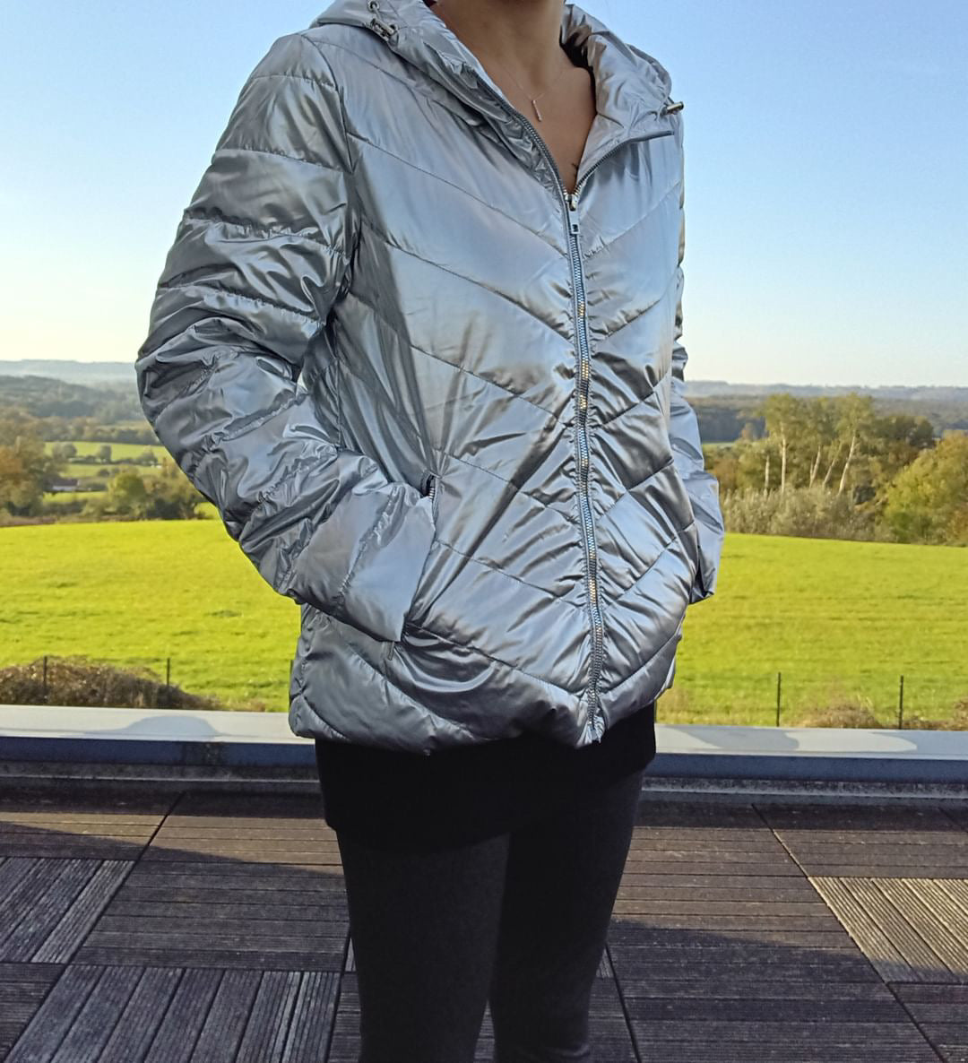 Woman wearing a shiny silver Laura Jo puffer jacket outdoors, modern fashion by Le Petit Placard