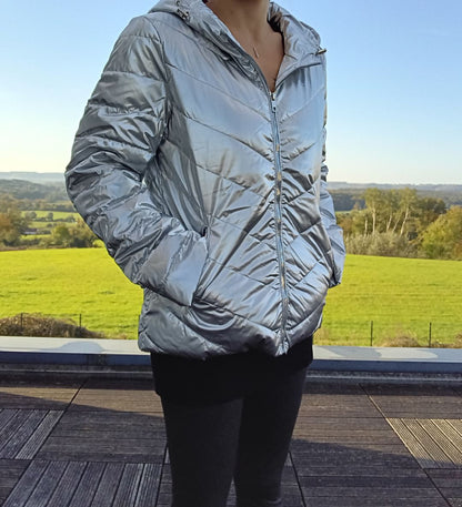 Woman wearing a shiny silver Laura Jo puffer jacket outdoors, modern fashion by Le Petit Placard
