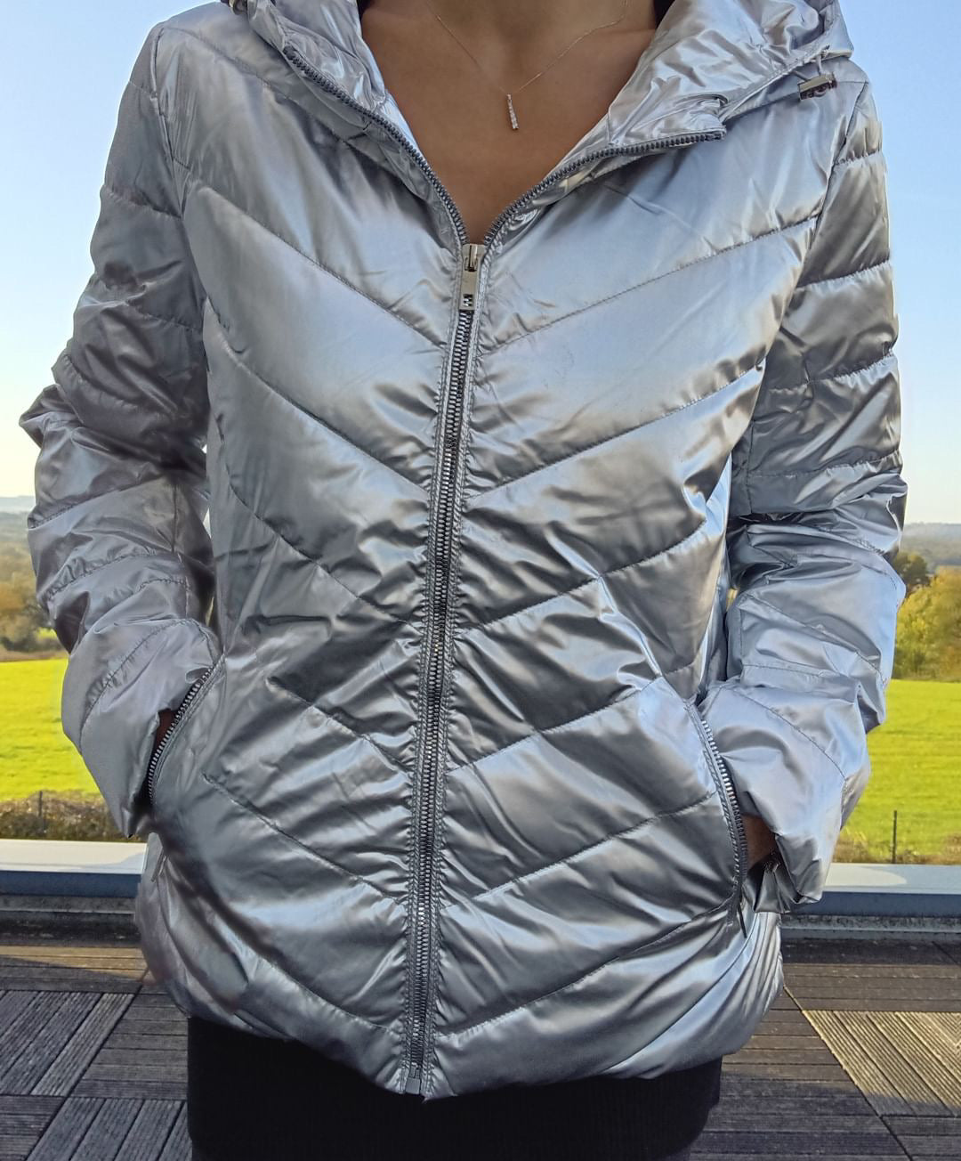Woman wearing a shiny silver Laura Jo puffer jacket outdoors, Le Petit Placard fashion.