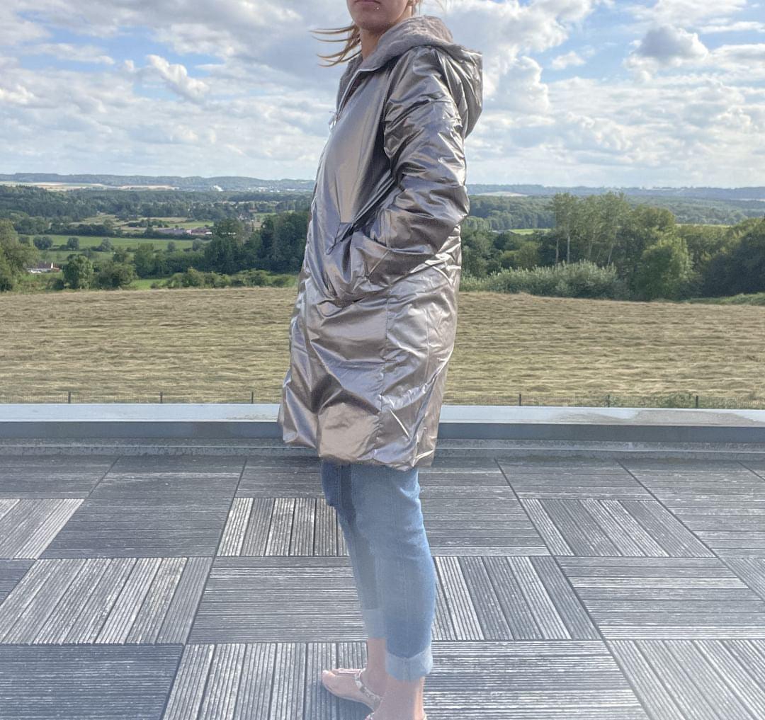 Manteau réversible grande taille Melya Melody côté imperméable bronze, porté de profil sur une terrasse extérieure