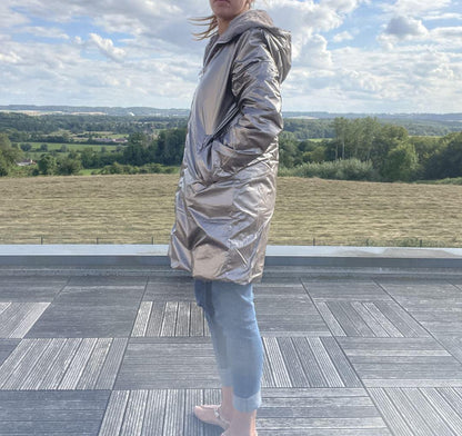 Manteau réversible grande taille Melya Melody côté imperméable bronze, porté de profil sur une terrasse extérieure