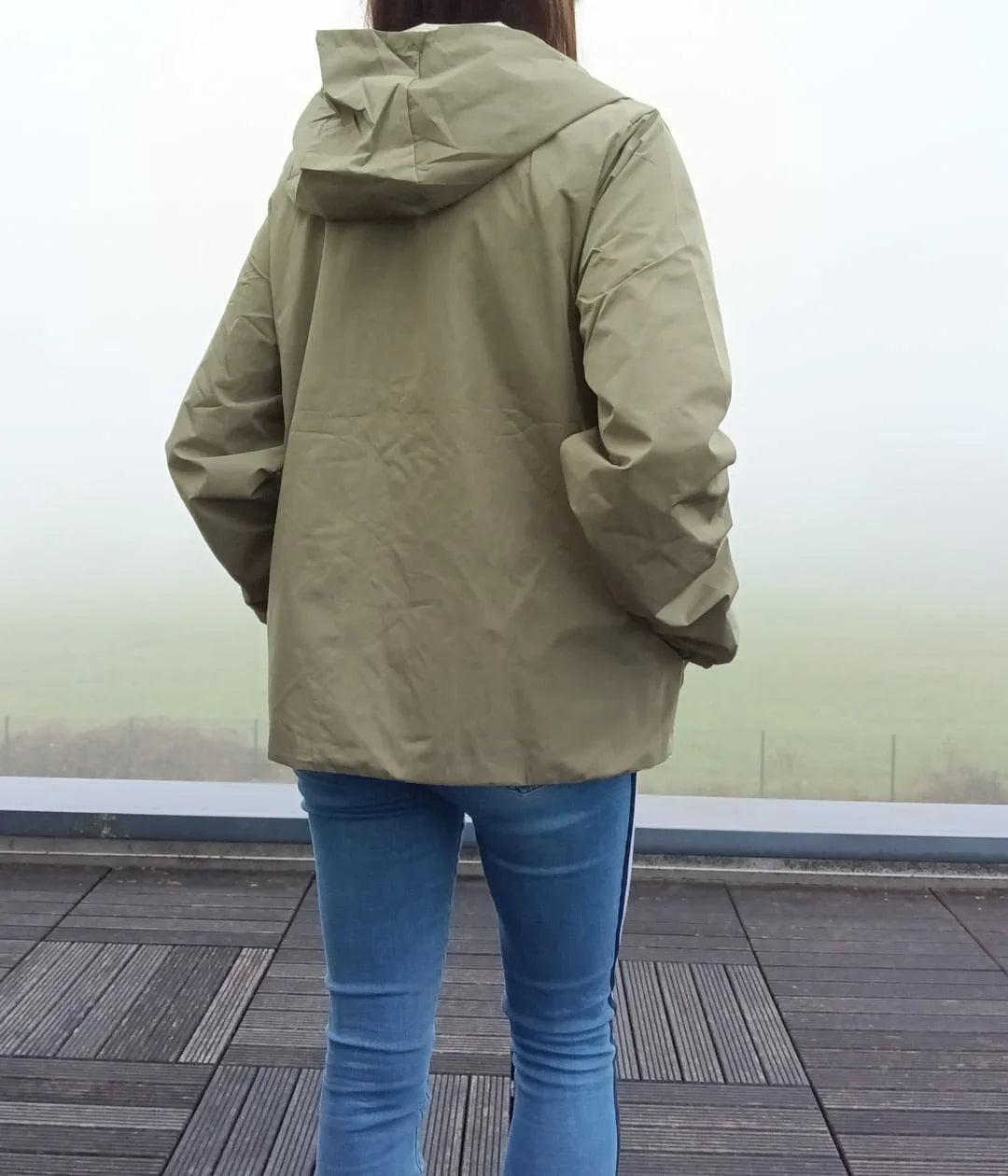 Manteau court kaki imperméable réversible avec capuche portée vue de dos sur une personne.