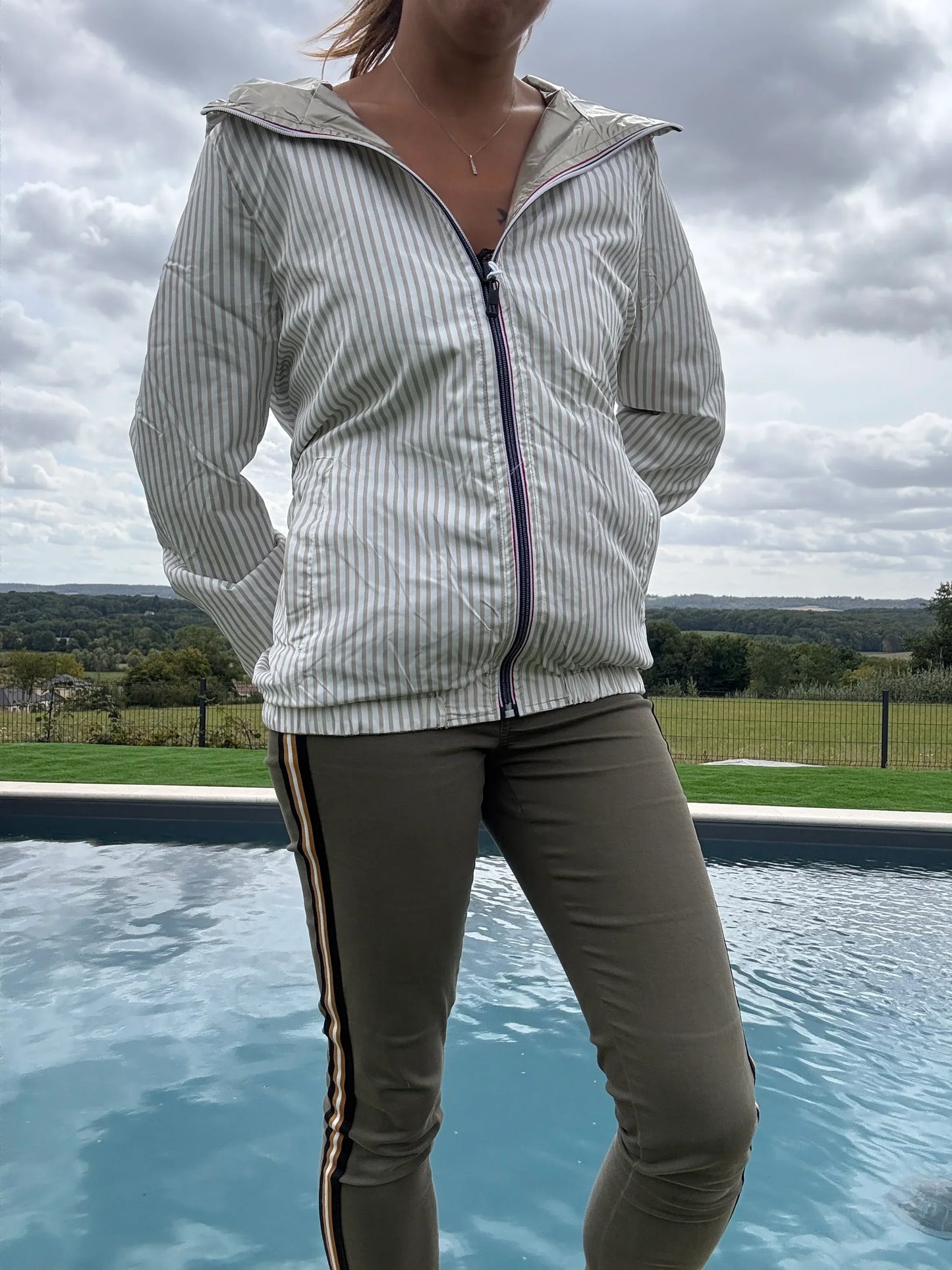 Manteau court réversible imperméable Le Petit Placard avec capuche, intérieur marin doré, beige et blanc, porté en extérieur.