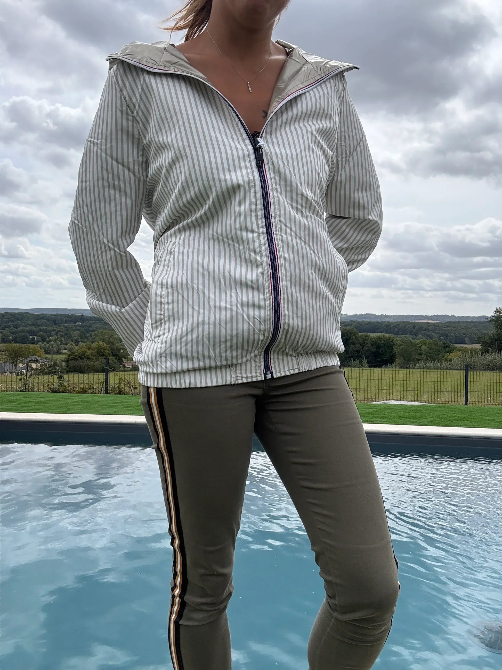 Manteau court réversible imperméable Le Petit Placard avec capuche, intérieur marin doré, beige et blanc, porté en extérieur.