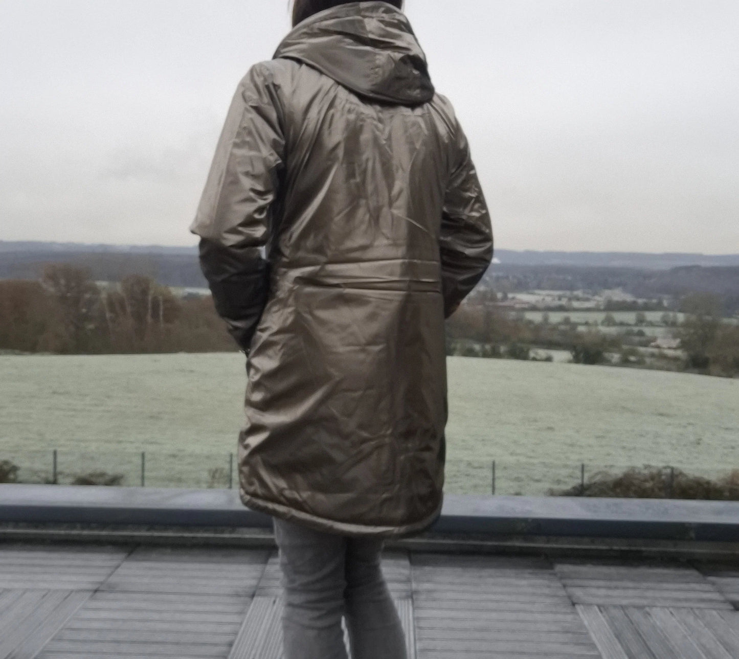 Parka imperméable longue fourrée femme Laura Jo bronze avec capuche, vue de dos sur terrasse
