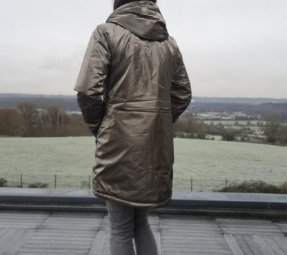 Parka imperméable longue fourrée femme Laura Jo bronze avec capuche, vue de dos sur terrasse
