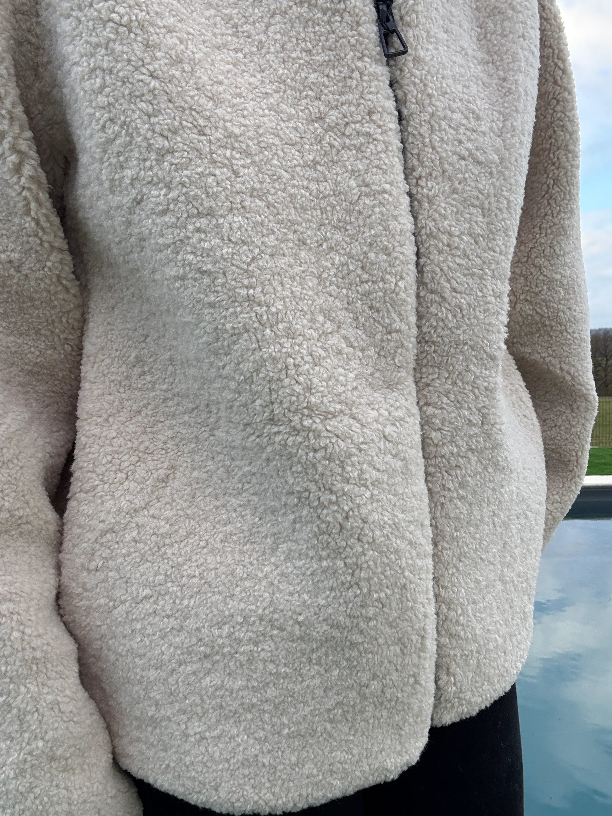 Gros plan sur la doublure sherpa beige de la veste courte réversible femme Laura Jo, texture bouclée douce avec fermeture éclair noire