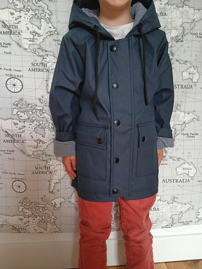 Child wearing navy blue raincoat with striped cotton lining from Le Petit Placard, map background.