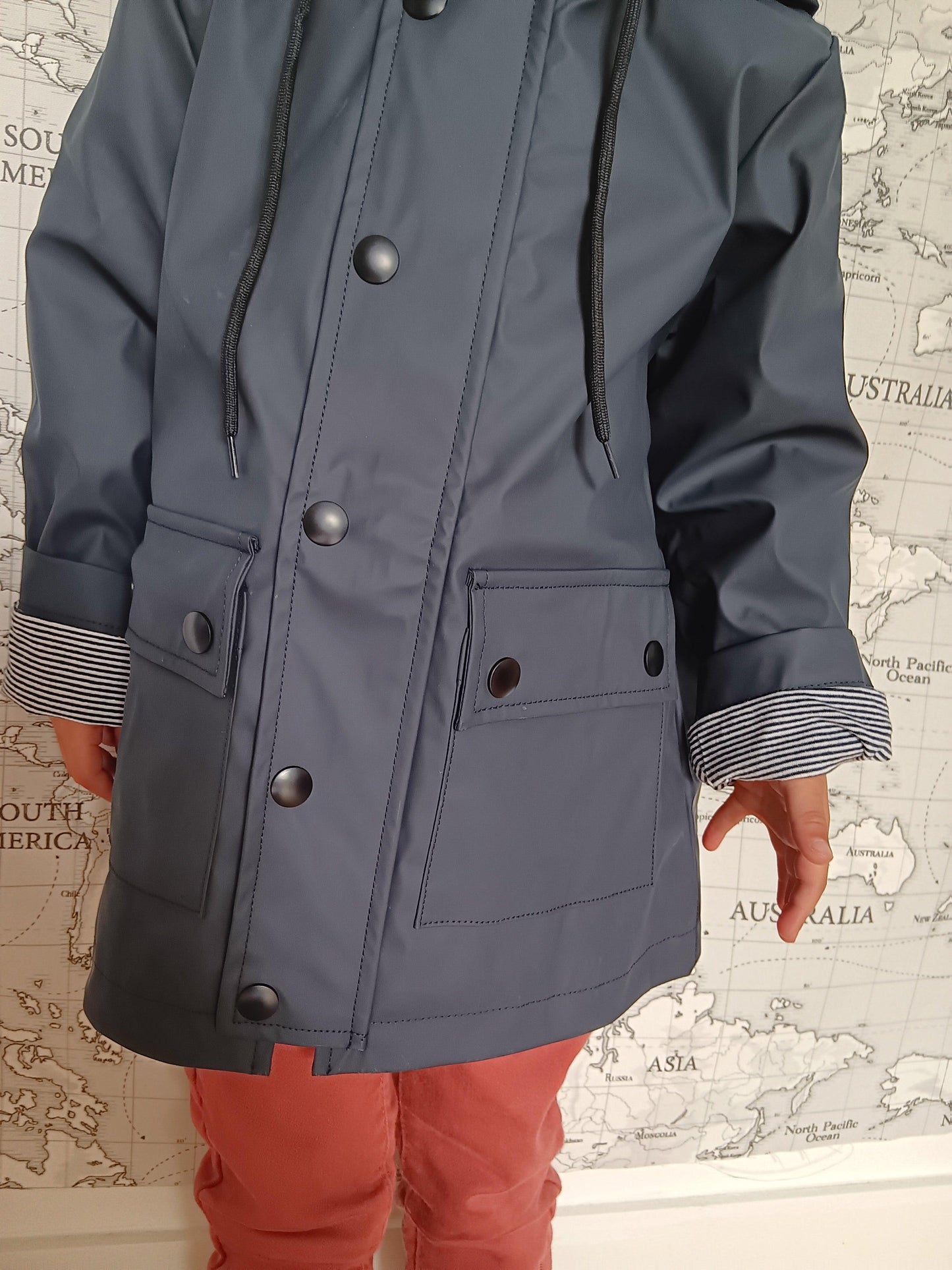 Child wearing navy blue raincoat with striped cotton lining, Le Petit Placard outerwear.