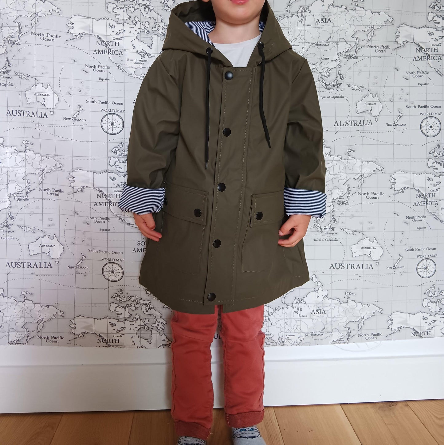 Child wearing khaki raincoat with striped cotton lining, Le Petit Placard style, map backdrop.