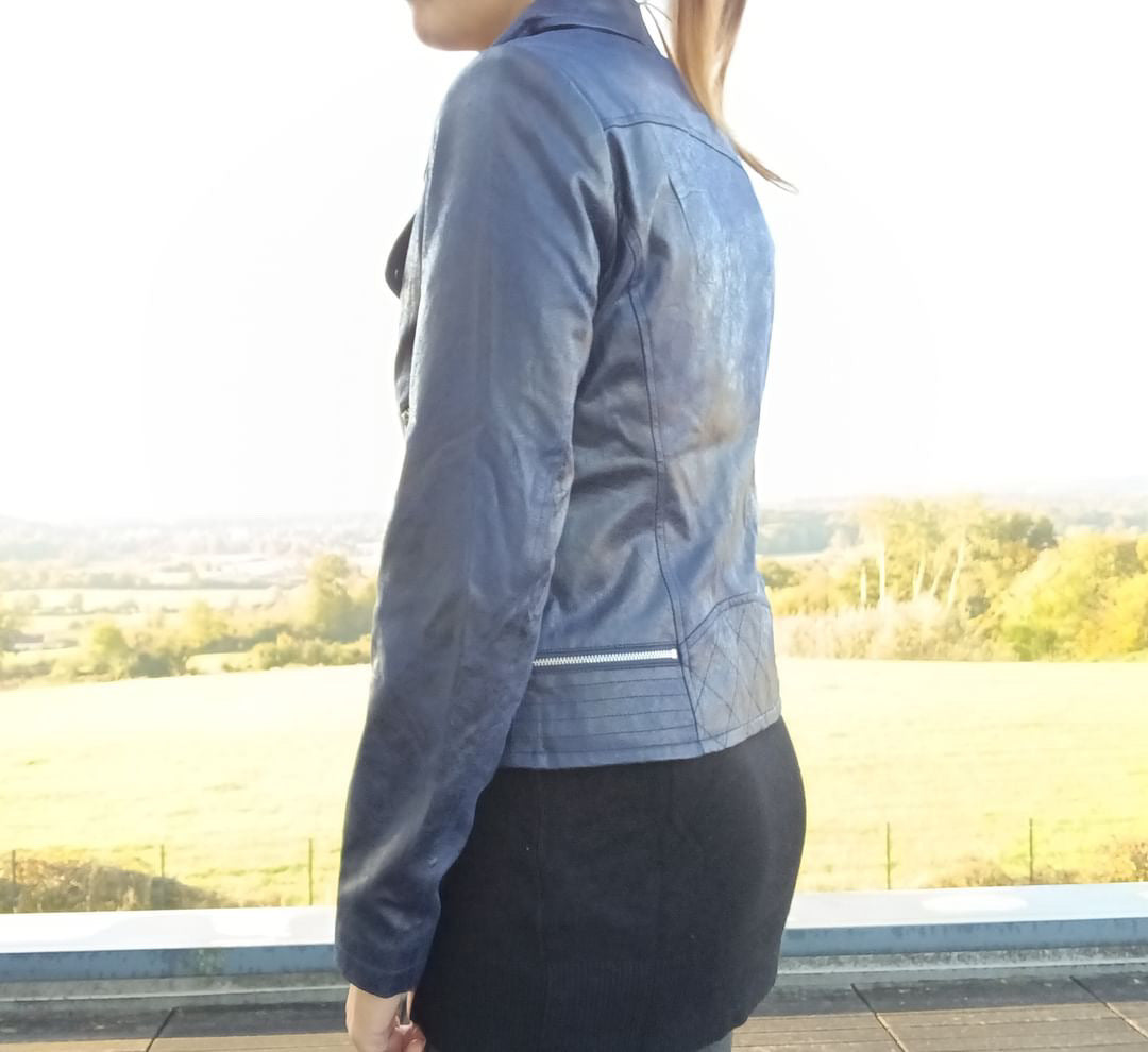 Woman wearing a stylish blue jacket from Le Petit Placard, outdoors with nature view