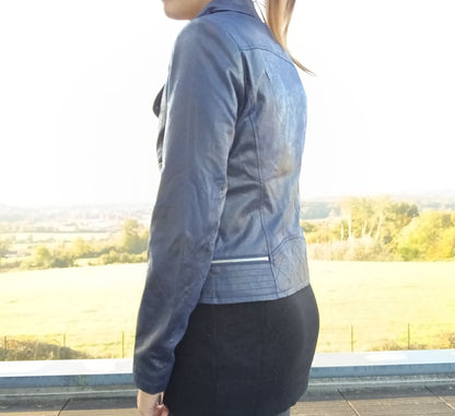 Woman wearing a stylish blue jacket from Le Petit Placard, outdoors with nature view