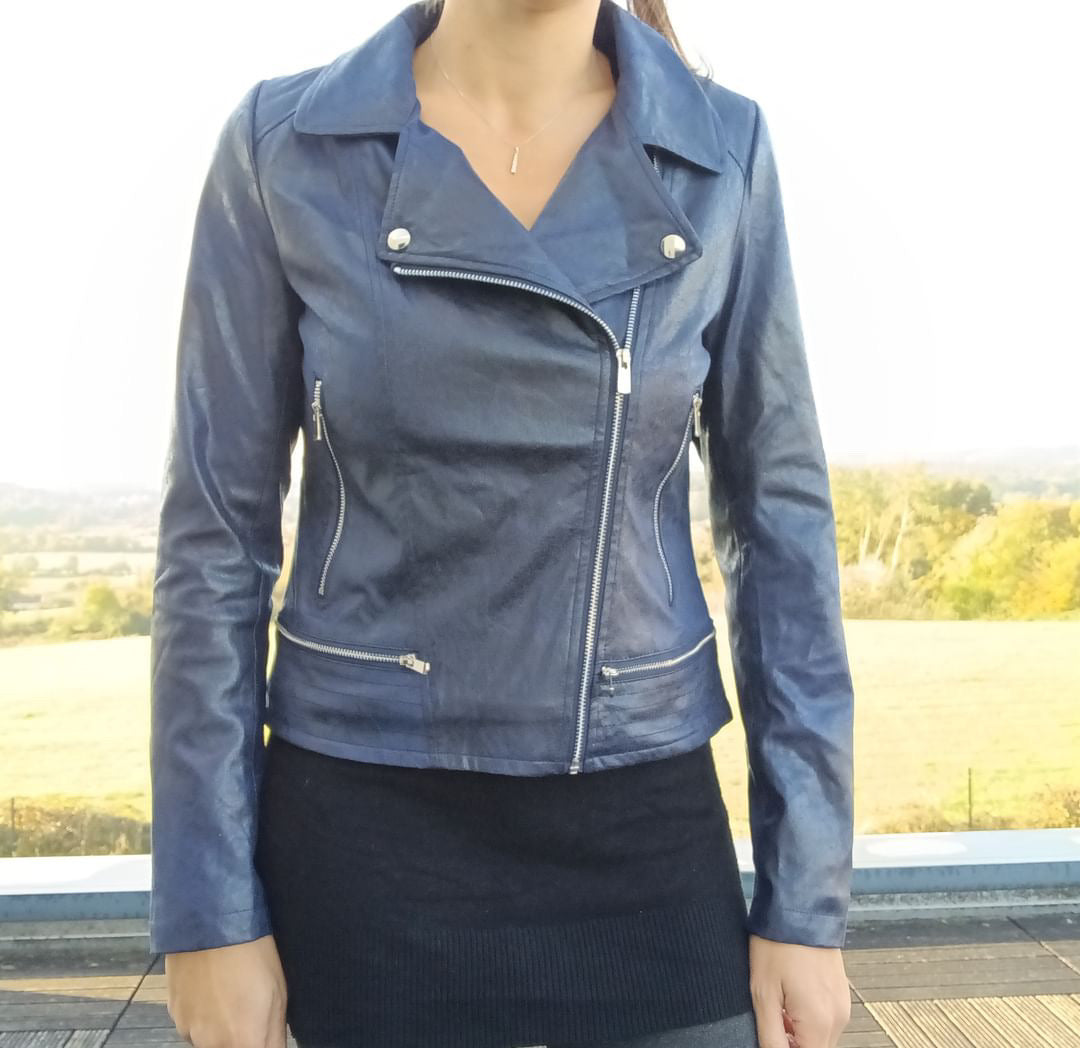 Woman wearing a blue faux leather biker jacket from Le Petit Placard outdoors