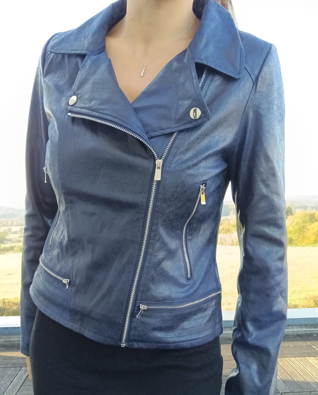 Woman wearing a stylish blue faux leather jacket with zip details, outdoor background, Le Petit Placard