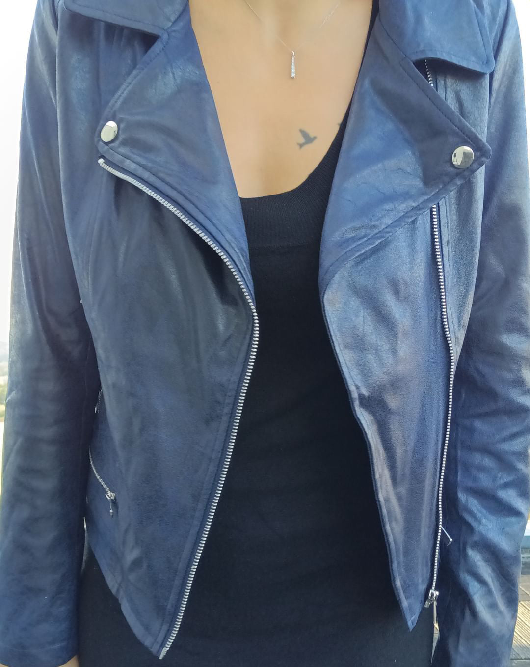 Woman wearing a navy blue perfecto jacket from Le Petit Placard over a black top