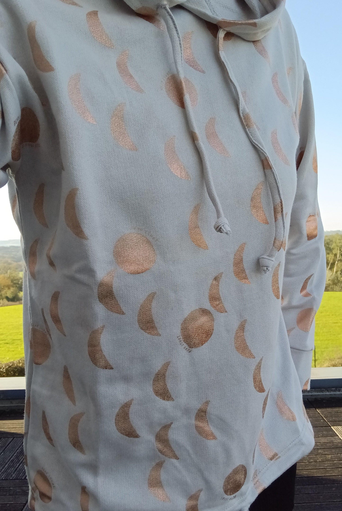 Sweat à capuche blanc crème avec cordon et motifs lune doré rosé représentant les phases lunaires