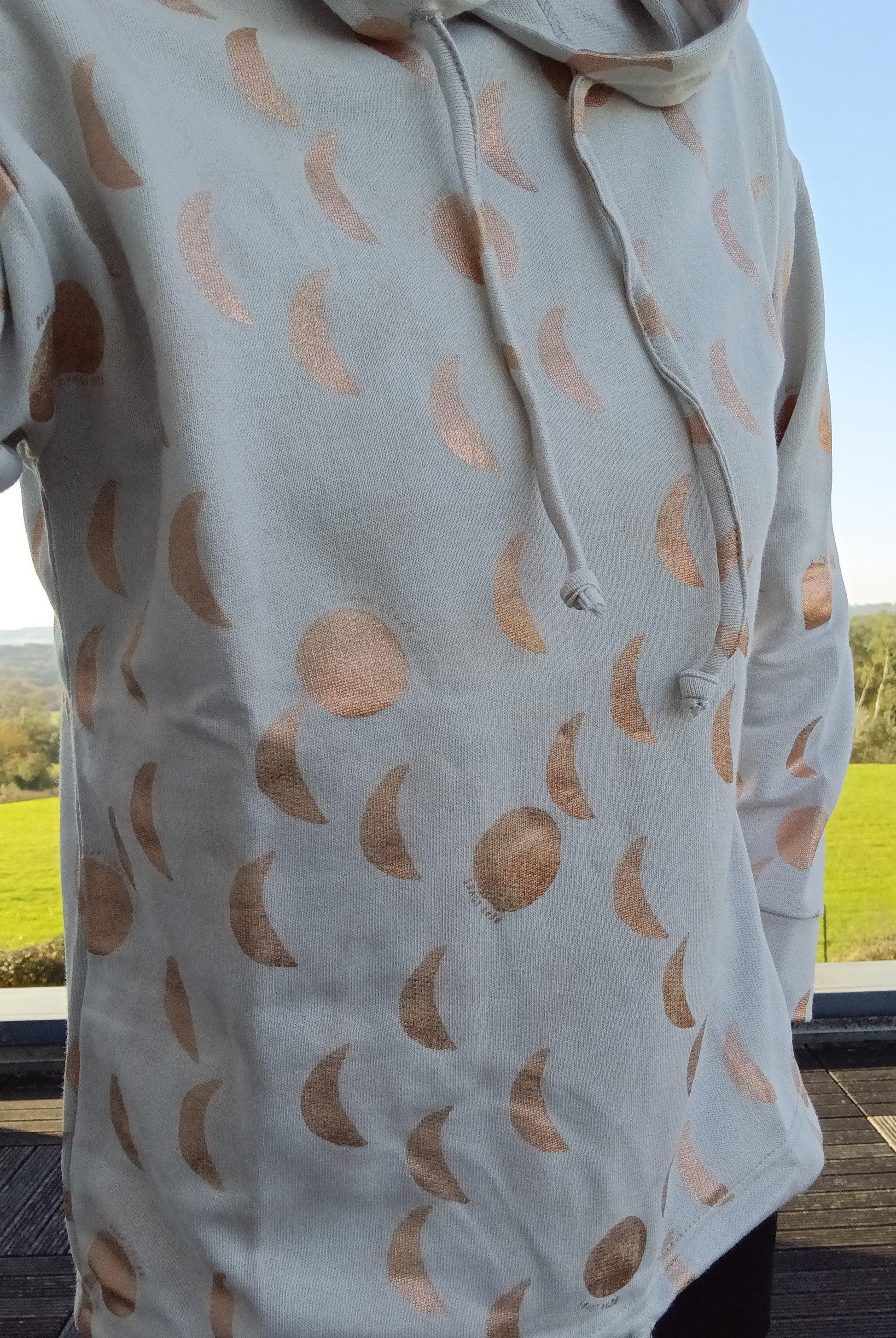 Sweat à capuche blanc crème avec cordon et motifs lune doré rosé représentant les phases lunaires