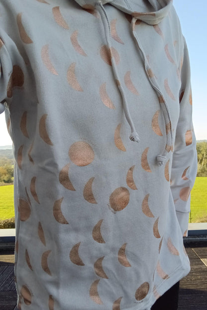 Sweat à capuche blanc crème avec cordon et motifs lune doré rosé représentant les phases lunaires