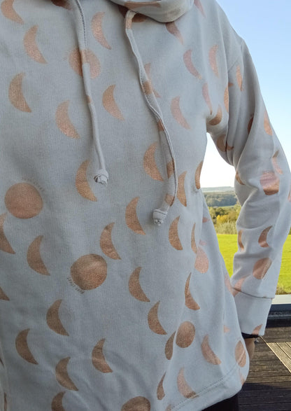 Sweat à capuche blanc crème avec cordon et motifs lune doré rosé, porté en extérieur