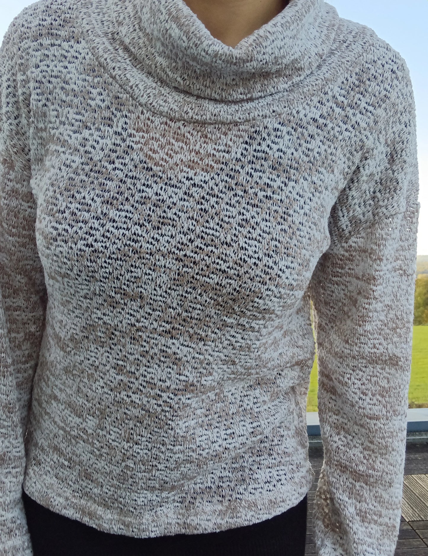 Pull col montant à grosses mailles beige taupe porté par une femme, tricot ajouré chiné doux et élégant