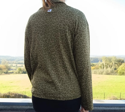 Pull fin col montant motifs léopard kaki porté de dos, vue sur campagne verdoyante