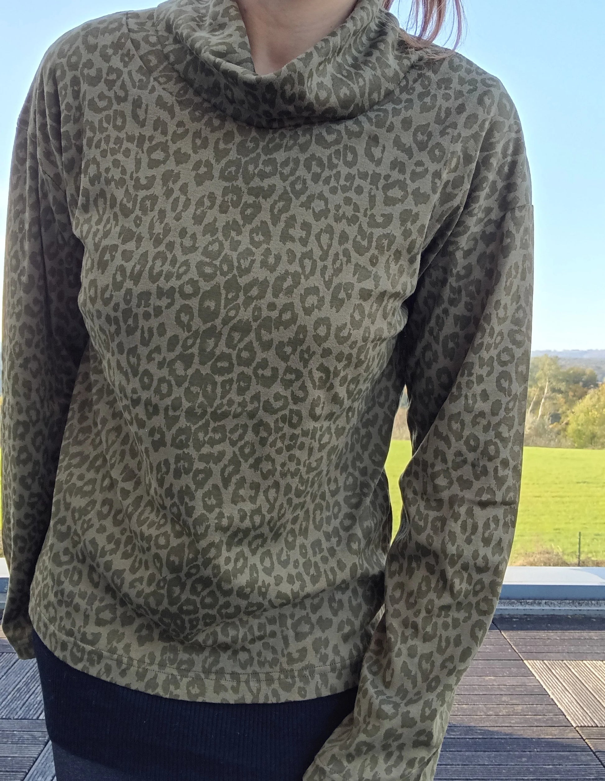 Pull fin col montant motifs léopard kaki porté par une femme, manches longues, coupe ajustée