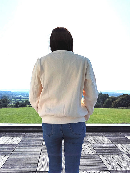 Woman in cream jacket and jeans on terrace with scenic countryside view, Le Petit Placard fashion
