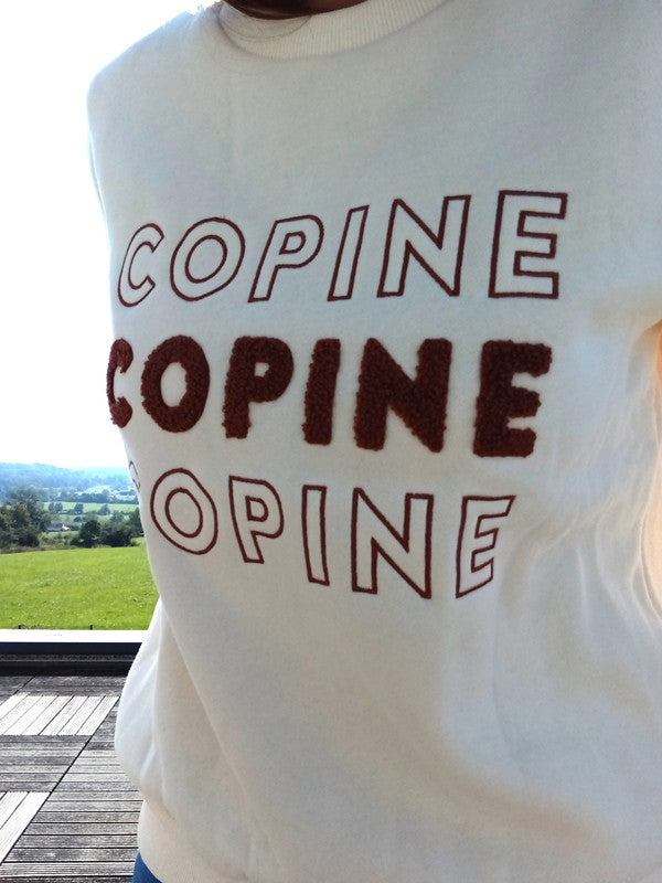 White sweatshirt with 'COPINE' text design, worn outdoors, Le Petit Placard fashion style