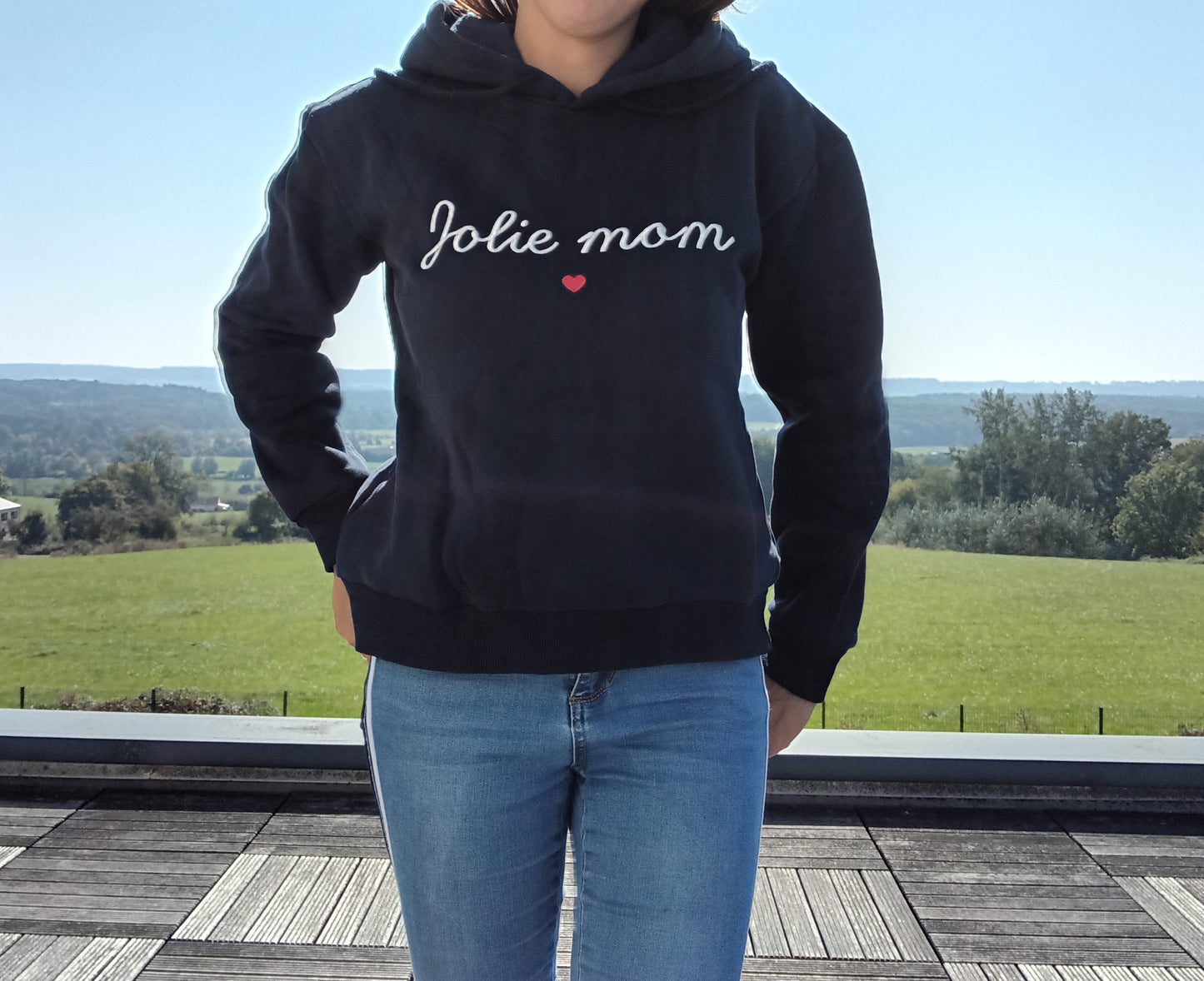 Woman wearing black 'Jolie mom' hoodie and jeans outdoors, Le Petit Placard fashion