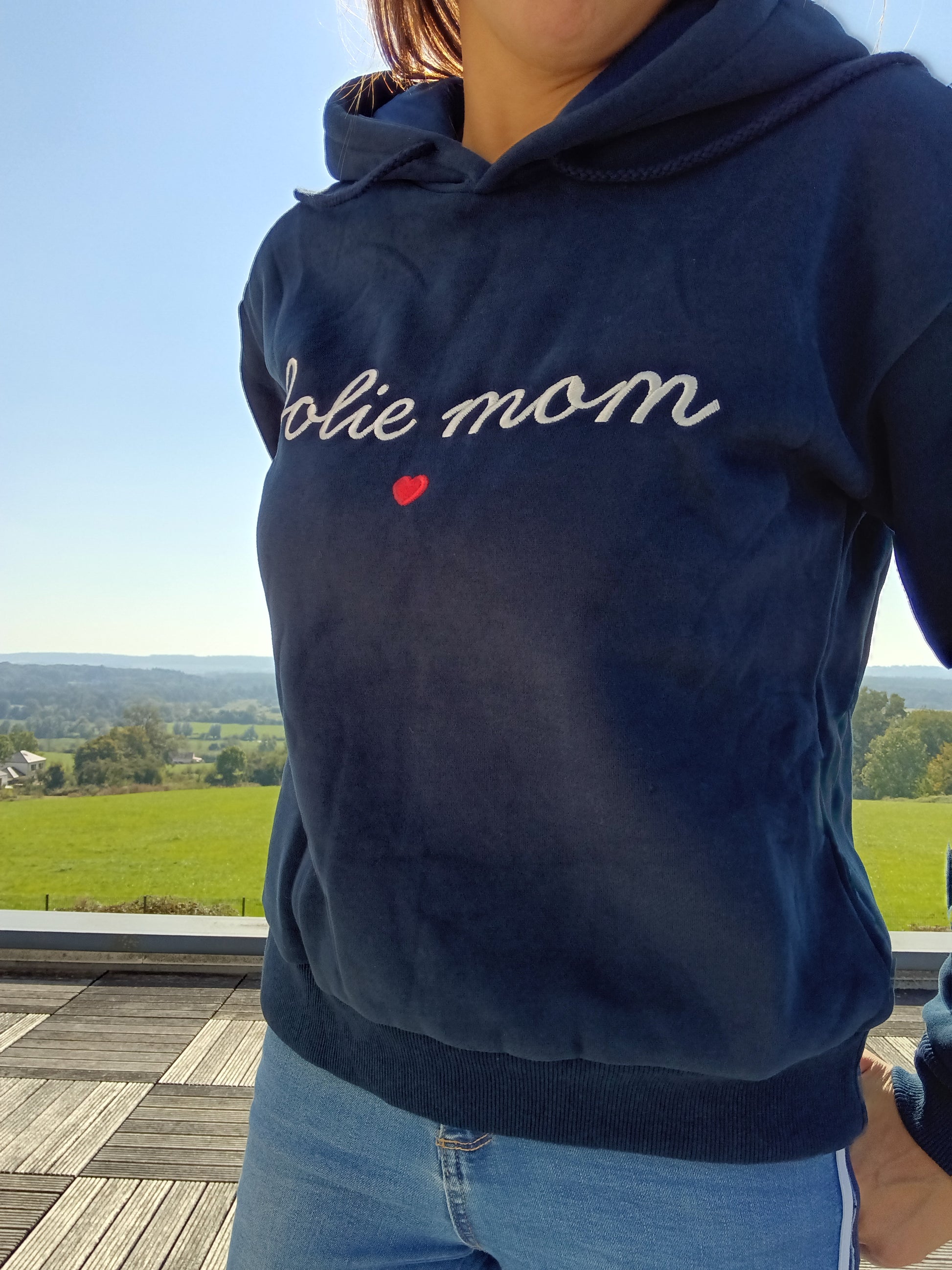 Woman wearing navy Jolie mom hoodie from Le Petit Placard, outdoors with scenic view
