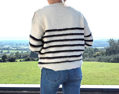 Pull fond blanc double rayures bleu marine et doré porté de dos avec jean, vue sur paysage verdoyant