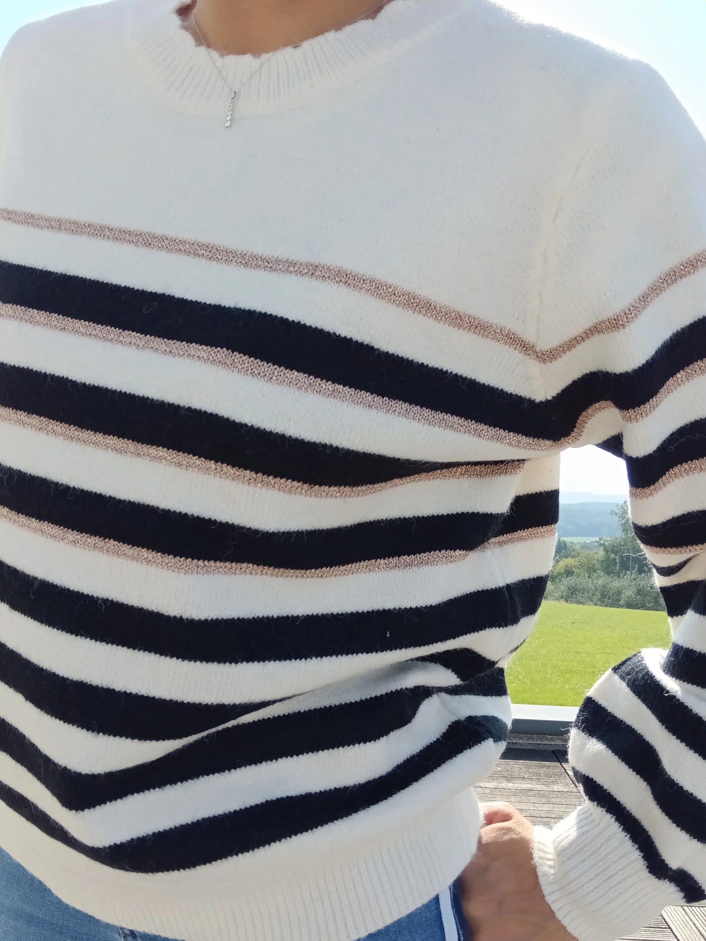 Pull fond blanc larges rayures noires avec fines rayures dorées porté par une femme, vue rapprochée