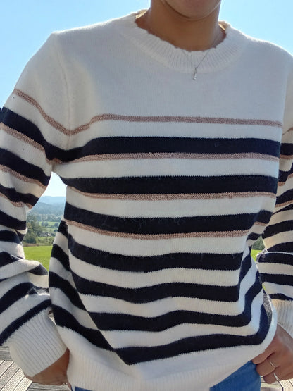 Pull fond blanc larges rayures noires et fines rayures dorées porté par une femme en extérieur