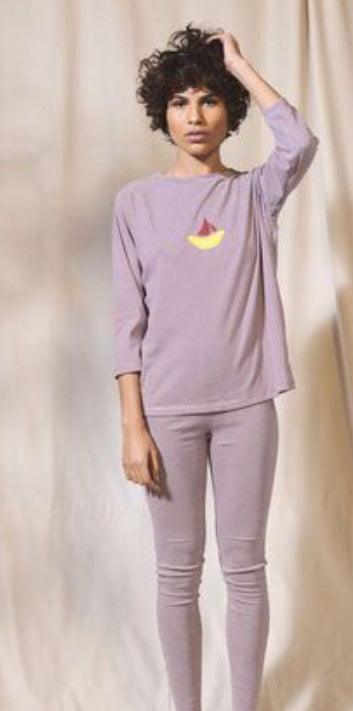 Woman wearing lavender Petit Bateau pyjamas with yellow boat logo, neutral background
