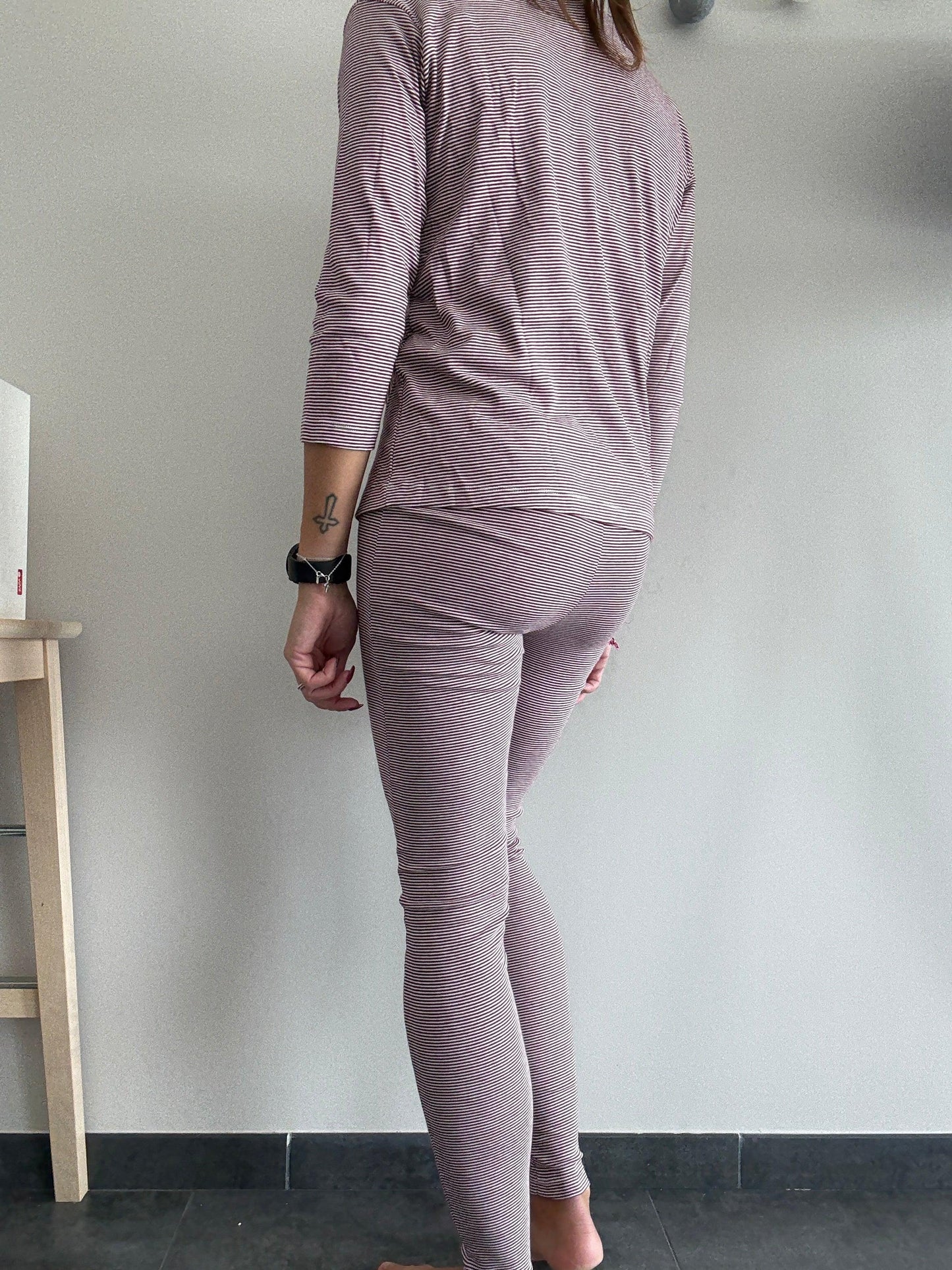 Woman wearing striped mauve pajamas, standing indoors on dark tile, Le Petit Placard fashion.