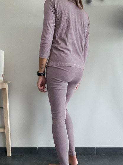 Woman wearing striped mauve pajamas, standing indoors on dark tile, Le Petit Placard fashion.
