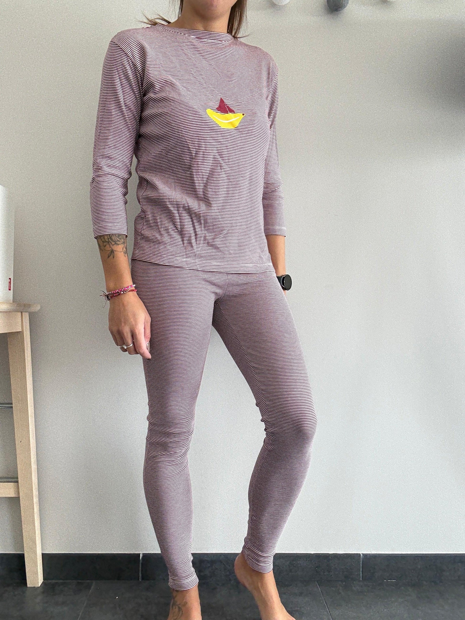 Woman wearing striped purple pajamas with a yellow boat print, Le Petit Placard fashion.