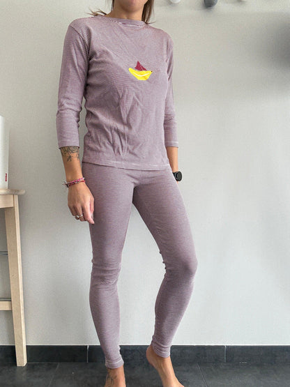 Woman wearing striped purple pajamas with a yellow boat print, Le Petit Placard fashion.