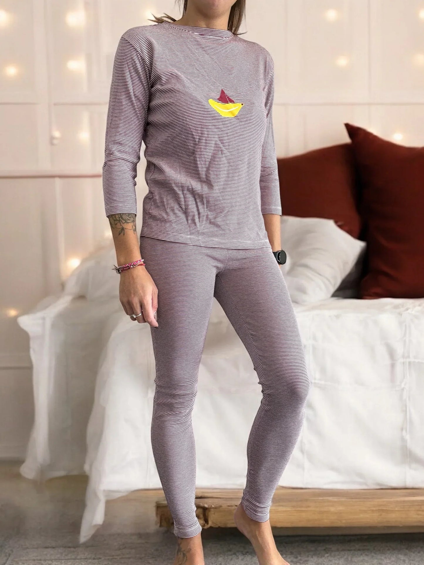 Woman wearing striped pajamas with sailboat print, standing in cozy bedroom, Le Petit Placard