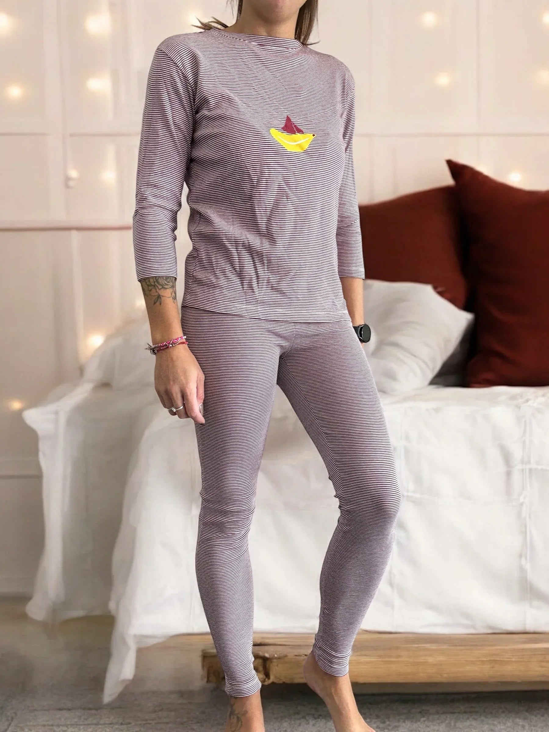 Woman wearing striped pajamas with sailboat print, standing in cozy bedroom, Le Petit Placard
