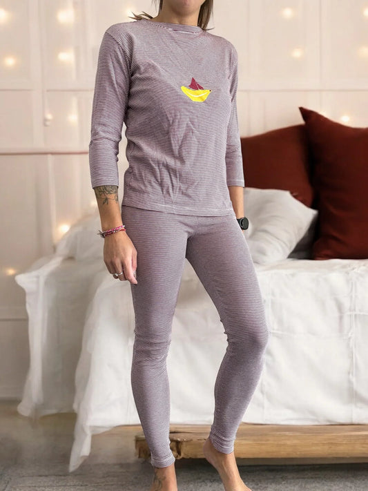 Woman wearing striped pajamas with sailboat print, standing in cozy bedroom, Le Petit Placard