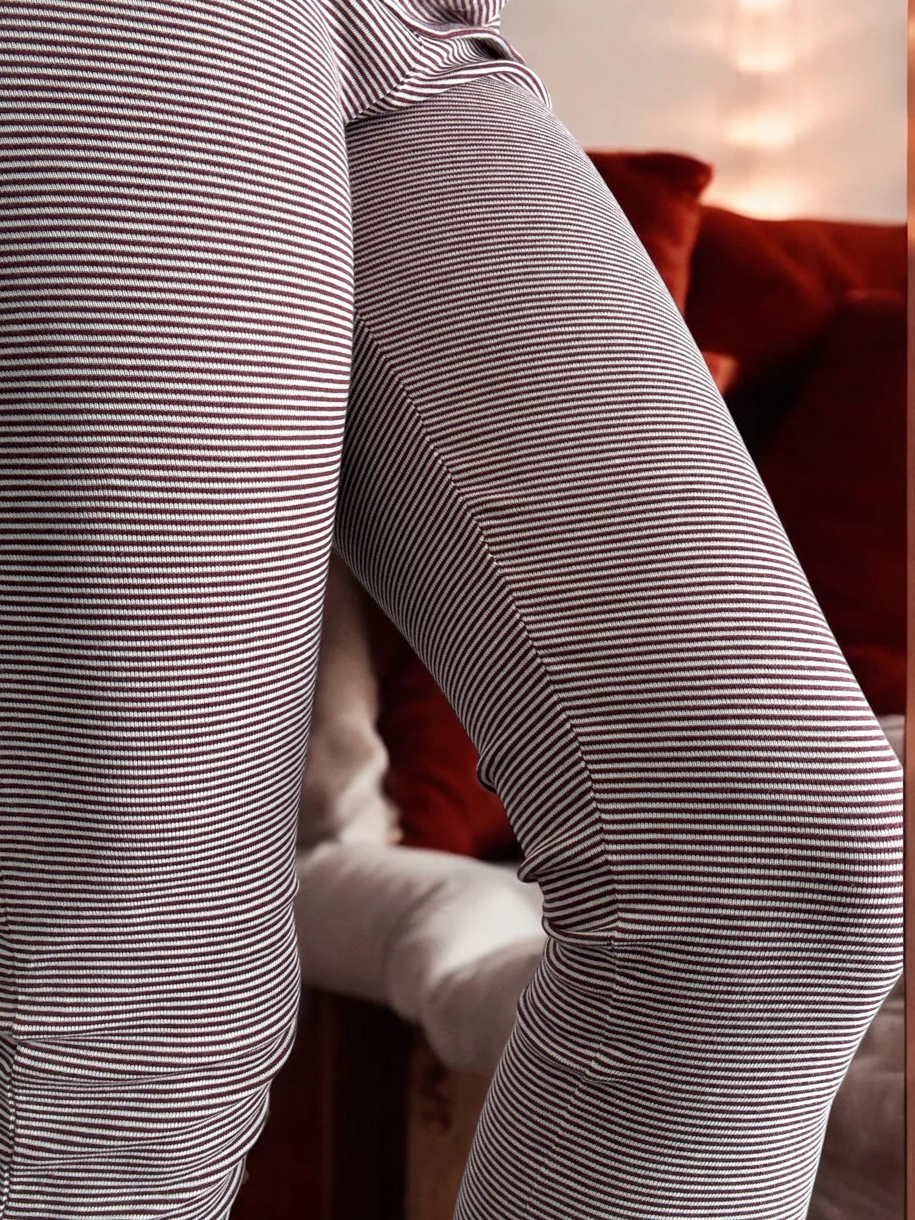 Close-up of striped leggings, cozy indoor setting with warm-toned cushions, Le Petit Placard
