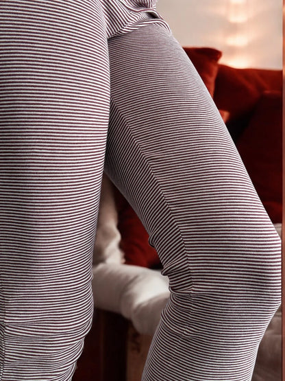 Close-up of striped leggings, cozy indoor setting with warm-toned cushions, Le Petit Placard