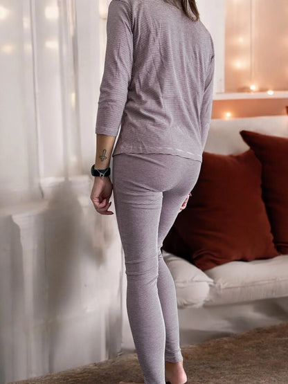 Woman in striped pajamas indoors, cozy setting with neutral decor and brown cushions
