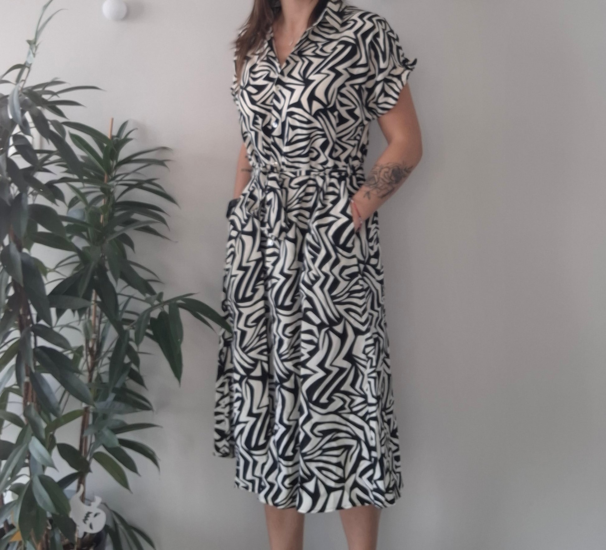 Woman in black and white zigzag patterned dress standing by a plant, Le Petit Placard fashion.